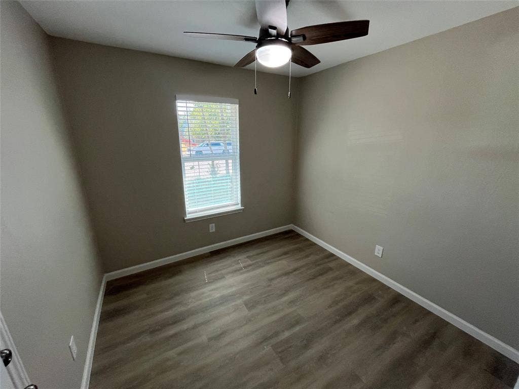 9615 Oak Gate Lane, Dallas, TX 75217 Wood-finish flooring, neutral wall tones, window with white blinds, and a ceiling fan with integrated lighting