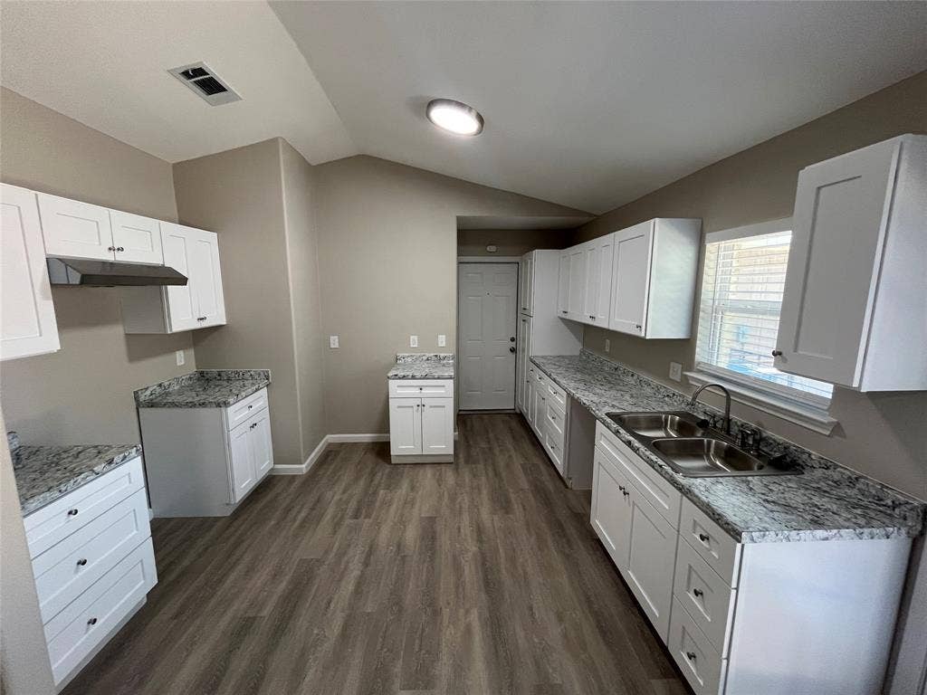 9615 Oak Gate Lane, Dallas, TX 75217 Spacious kitchen featuring white shaker cabinetry, granite-patterned countertops, wood-finish flooring, a double basin stainless steel sink, and a range hood
