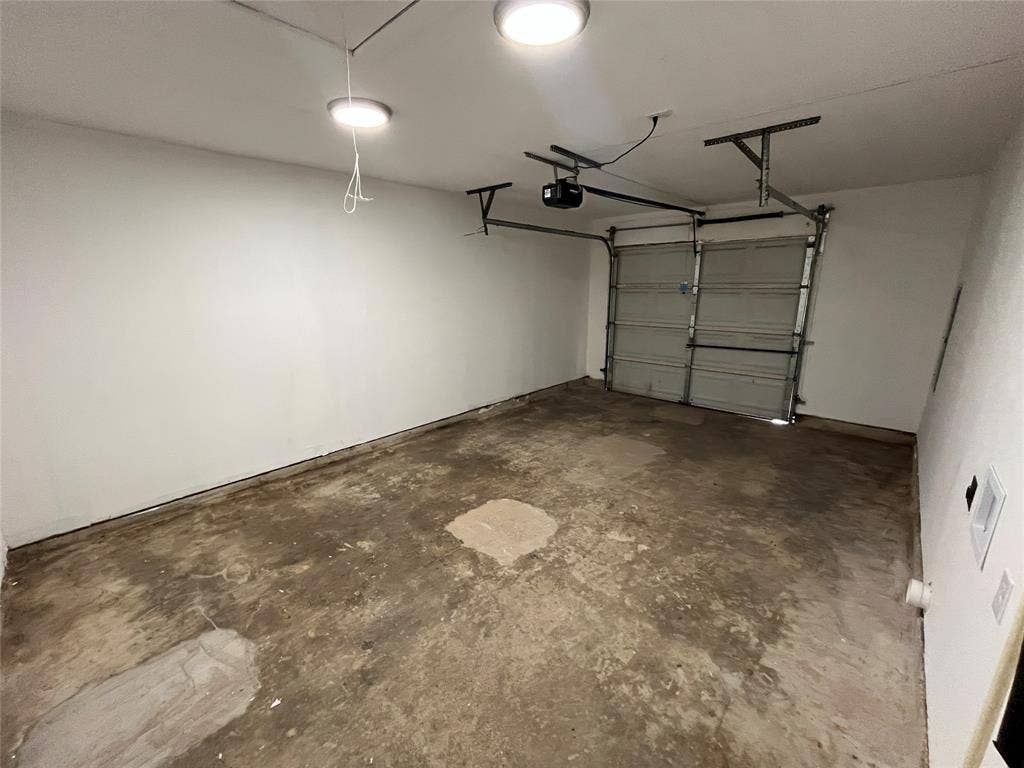 9615 Oak Gate Lane, Dallas, TX 75217 Garage space with a roll-up door and an automatic opener