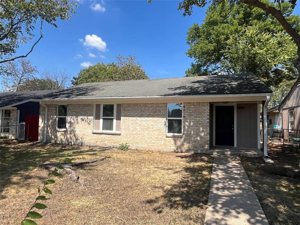 9615 Oak Gate Lane, Dallas, TX 75217 Brick exterior with a dark shingle roof, covered entry, and concrete walkway