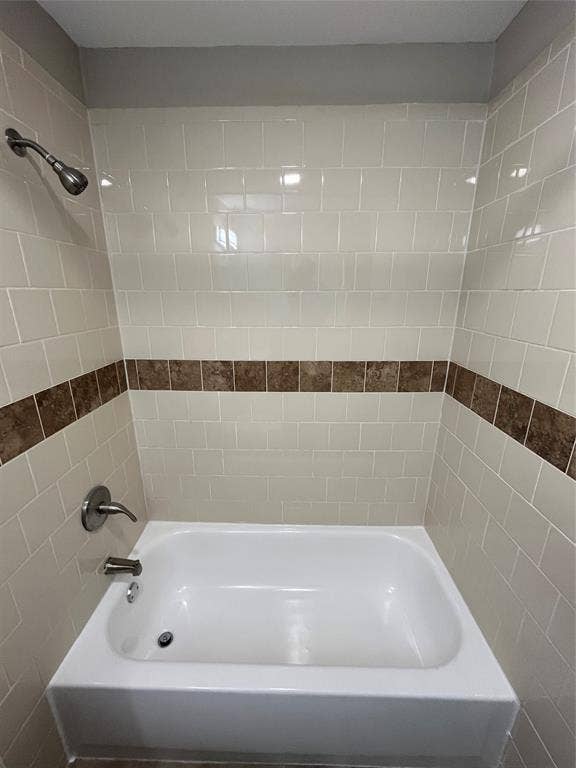 9615 Oak Gate Lane, Dallas, TX 75217 White subway tile surround with decorative accent band, white bathtub, and brushed nickel fixtures