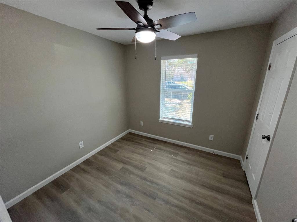 9615 Oak Gate Lane, Dallas, TX 75217 Wood-finish flooring, neutral wall tones, white trim, ceiling fan with integrated lighting, and window with blinds