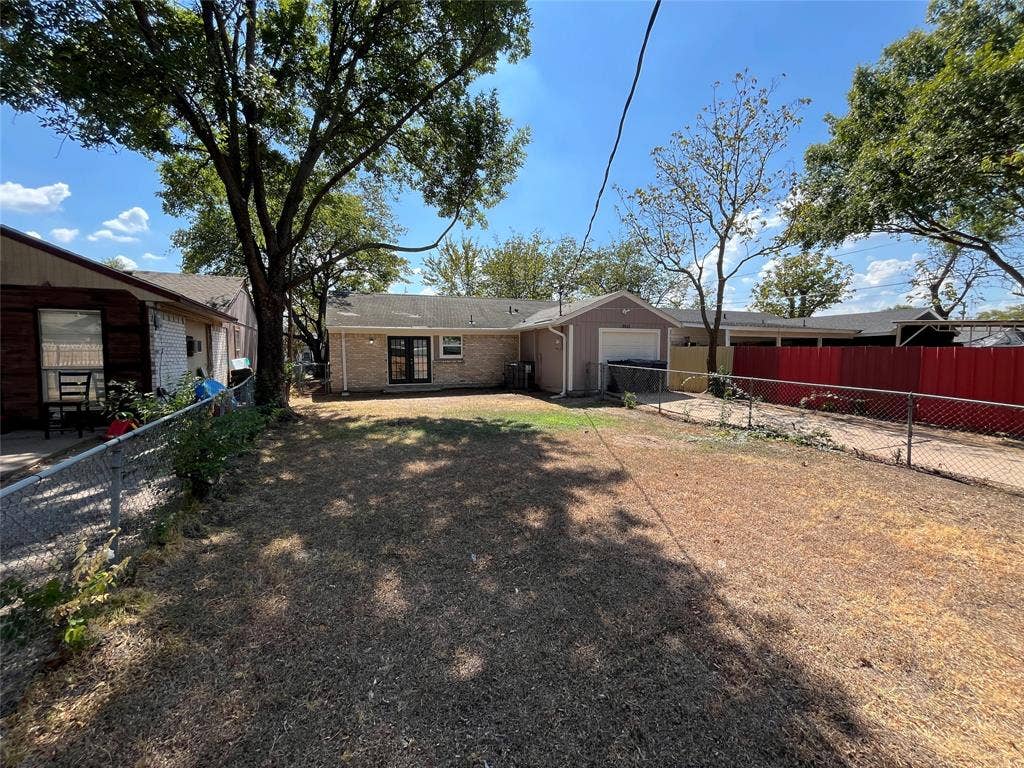 9615 Oak Gate Lane, Dallas, TX 75217 Chain link fencing enclosing the property, brick exterior, two-panel glass door, mature tree, attached garage