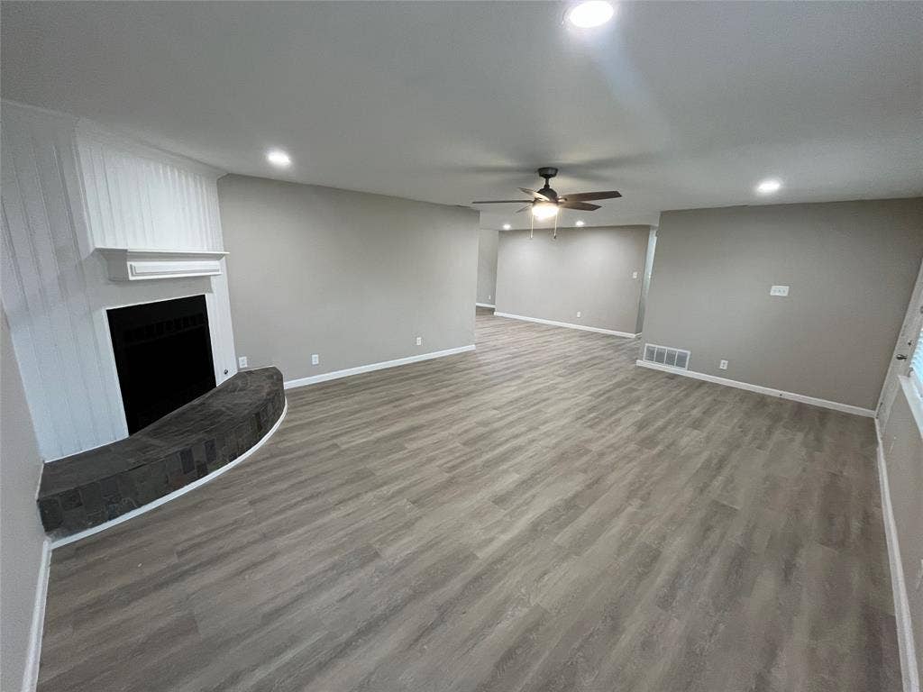 1831 Moonbeam Lane, Carrollton, TX 75006 Spacious living area featuring wood-finish flooring, a fireplace with a stone hearth, and recessed lighting