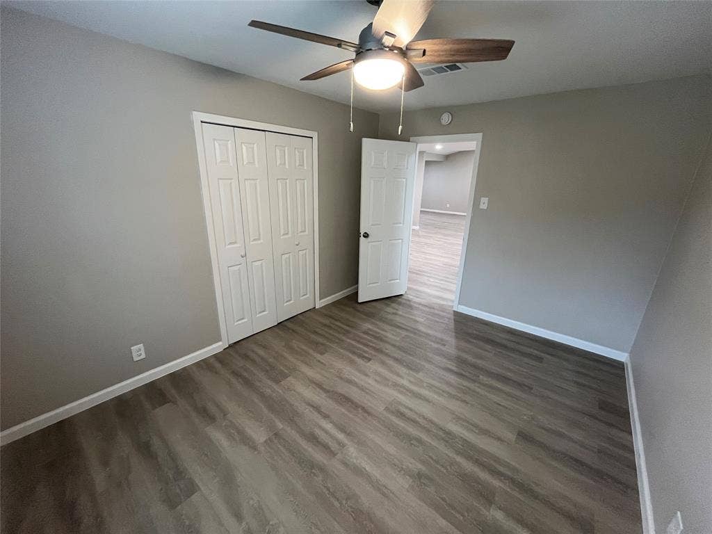 1831 Moonbeam Lane, Carrollton, TX 75006 Light gray wall color, wood-finish flooring, white trim, ceiling fan with integrated lighting, and a white bi-fold closet door
