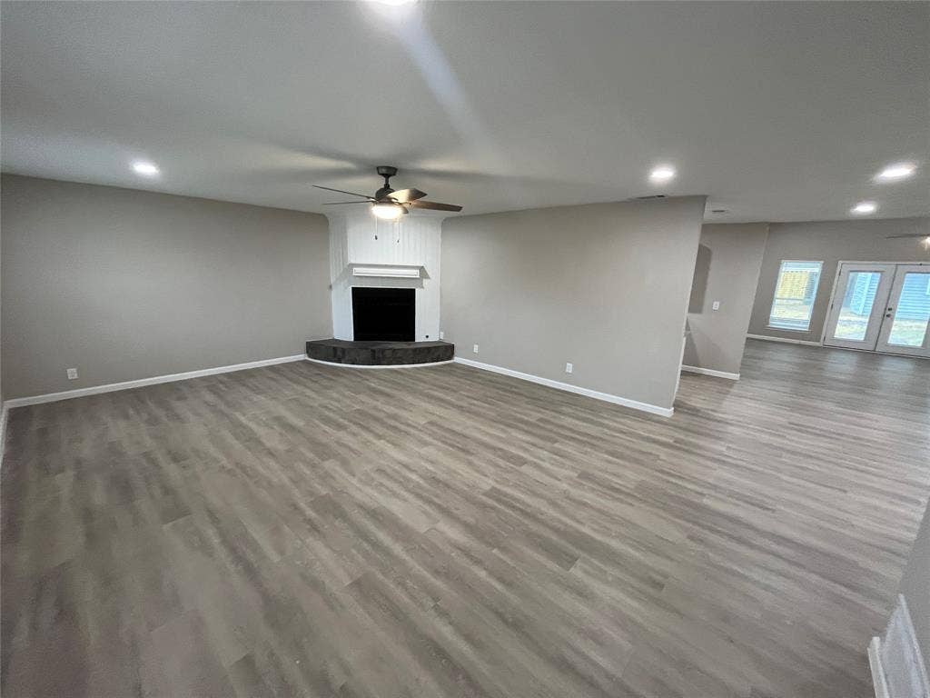 1831 Moonbeam Lane, Carrollton, TX 75006 Spacious living area featuring wood-finish flooring, recessed lighting, and a corner fireplace with a dark stone hearth