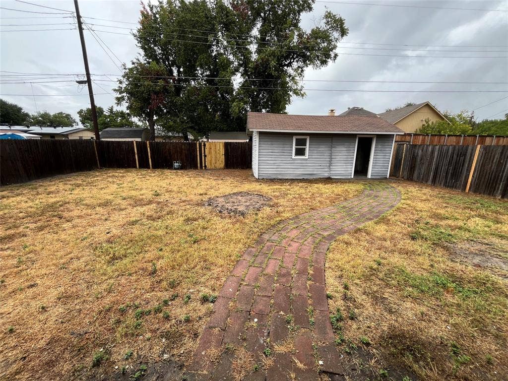 1831 Moonbeam Lane, Carrollton, TX 75006 Fenced backyard featuring a brick pathway and a detached storage shed