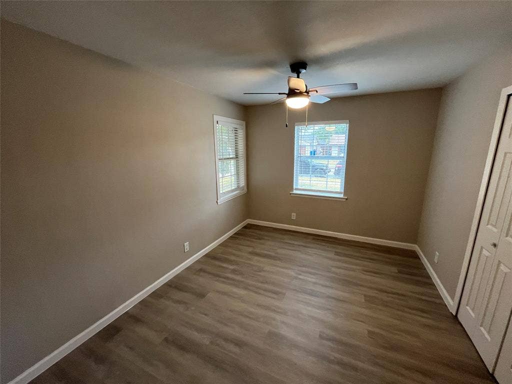 1831 Moonbeam Lane, Carrollton, TX 75006 Wood-finish flooring, neutral wall tones, two windows with blinds, a ceiling fan with integrated lighting, and a bi-fold closet door