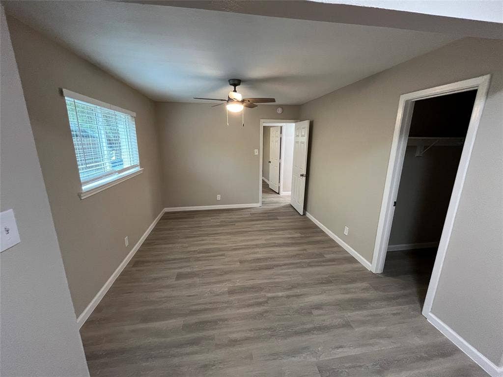 1831 Moonbeam Lane, Carrollton, TX 75006 Neutral wall paint, wood-finish flooring, ceiling fan with light fixture, window with blinds, and built-in closet shelving