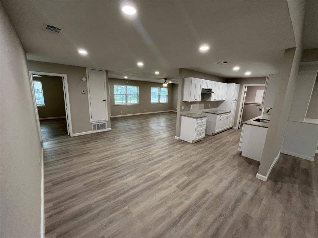 1831 Moonbeam Lane, Carrollton, TX 75006 Open-concept living space with recessed lighting, wood-finish flooring, white cabinetry, and granite countertops