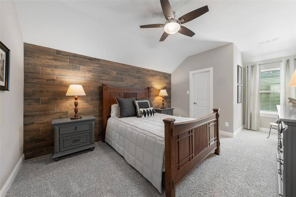 121 Lantana Lane, Wylie, TX 75098 Accent wall with wood-look planking, vaulted ceiling, ceiling fan with integrated lighting, window with blinds, and light gray wall paint
