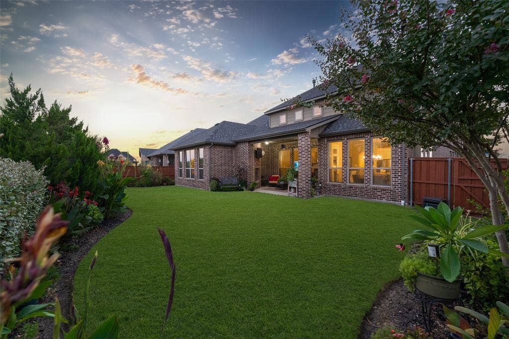 121 Lantana Lane, Wylie, TX 75098 Expansive green lawn with established landscaping, brick exterior, multiple windows, and a covered patio
