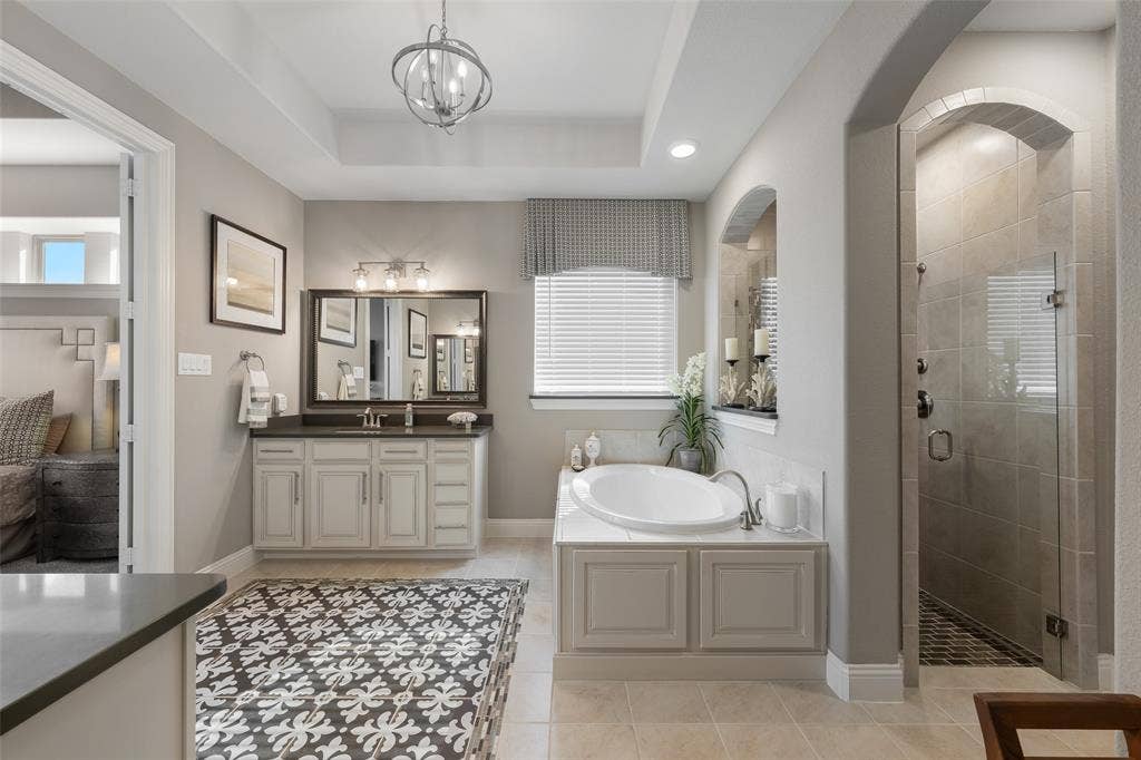 121 Lantana Lane, Wylie, TX 75098 Recessed lighting, large soaking tub, glass-enclosed shower, arched entryway, and a single vanity with dark countertop