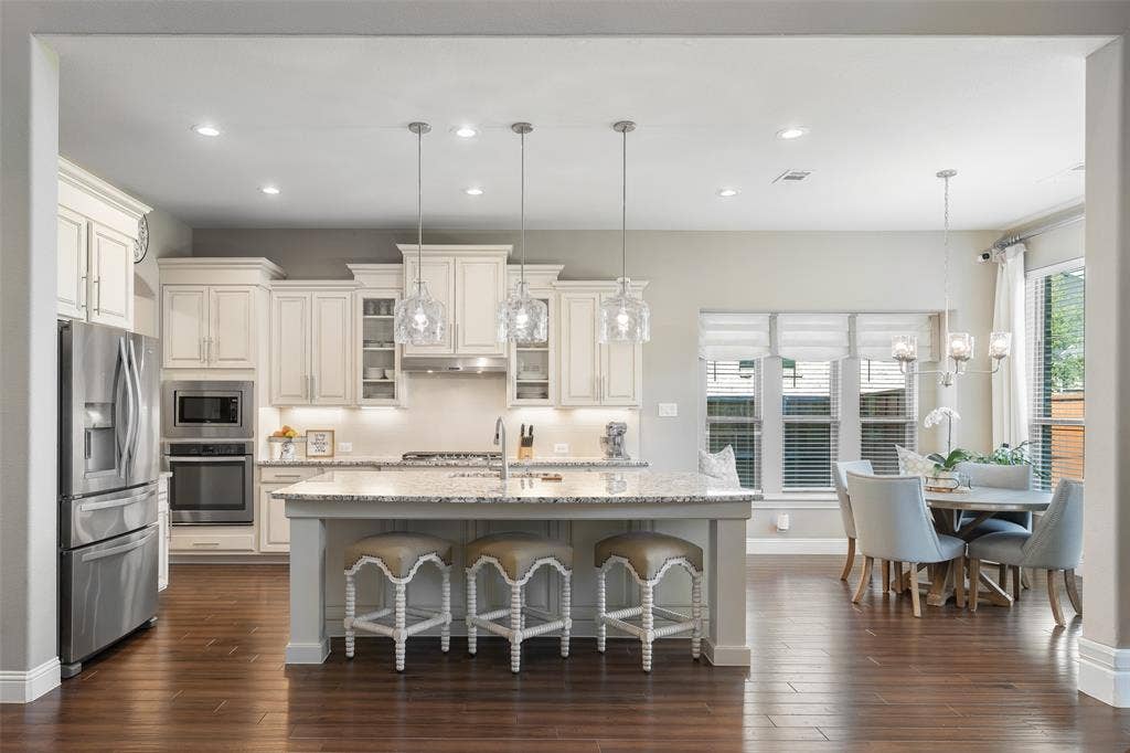 121 Lantana Lane, Wylie, TX 75098 Kitchen featuring a large island with pendant lighting, white cabinetry, stainless steel appliances, and wood-finish flooring