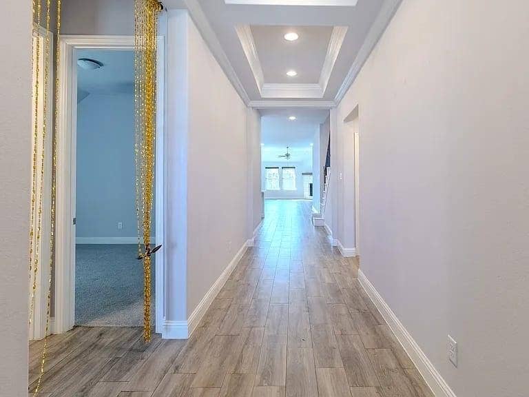 Recessed lighting, tray ceiling, wood-finish flooring, white baseboards, and white wall paint