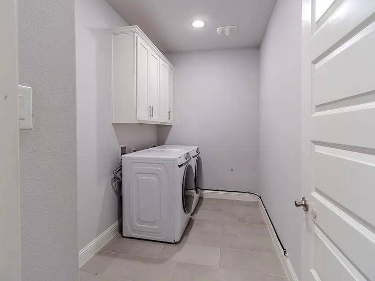 Laundry area featuring white cabinetry, a single overhead light, and a white paneled door