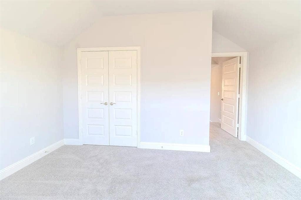 Vaulted ceiling, paneled double doors, light-toned carpeting, and crisp white trim
