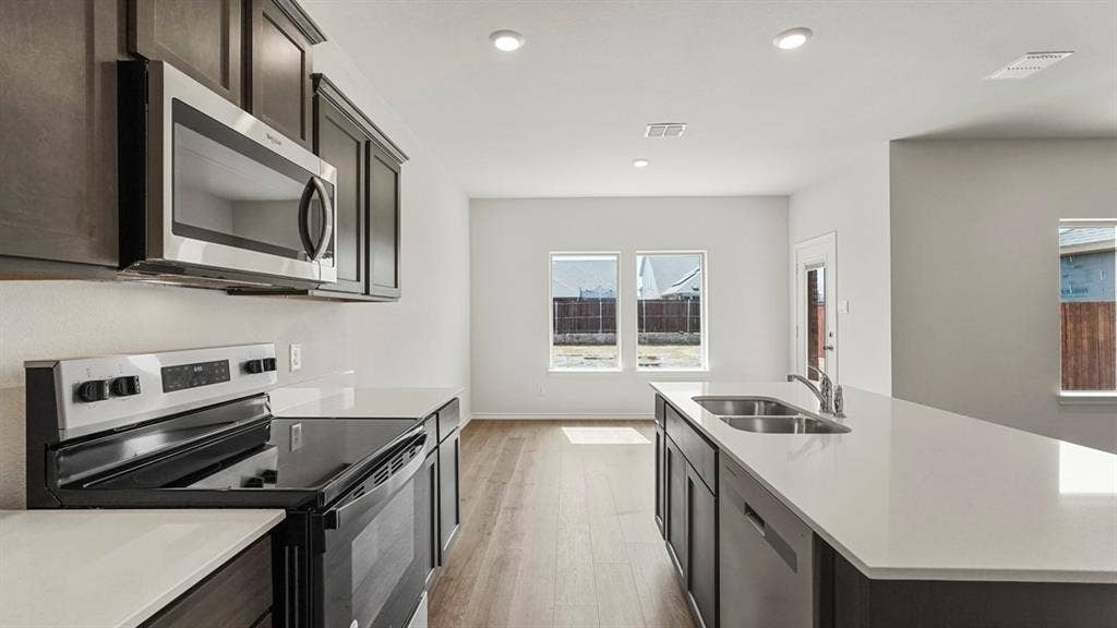 5610 Gannet Place, Crandall, TX 75114 Contemporary kitchen featuring dark cabinetry, stainless steel appliances, light countertops, wood-finish flooring, and recessed lighting