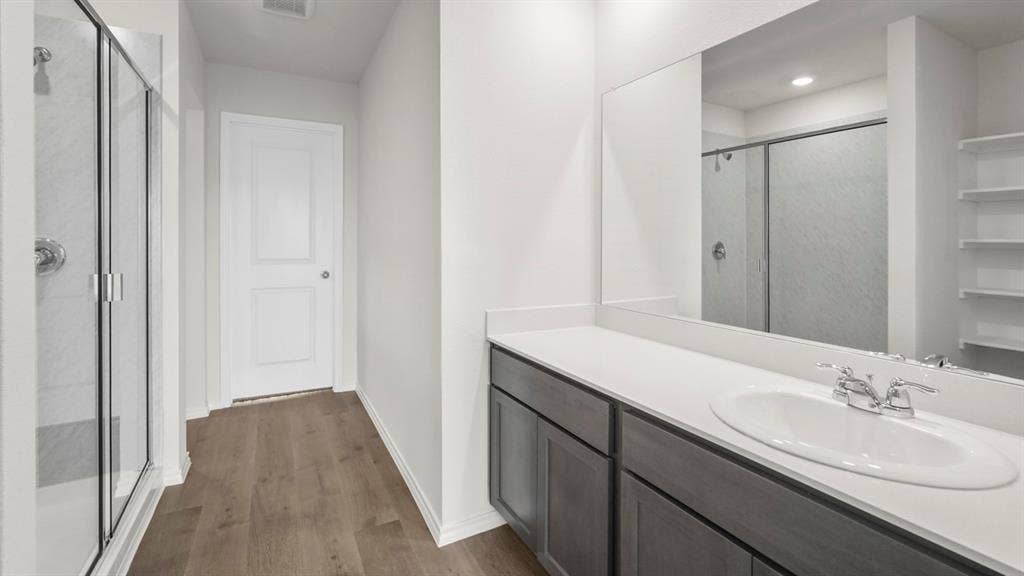 5610 Gannet Place, Crandall, TX 75114 Contemporary bathroom featuring a glass-enclosed shower with subway tile, wood-finish flooring, a white vanity with gray cabinetry, a quartz-finish countertop, and a large wall-mounted mirror