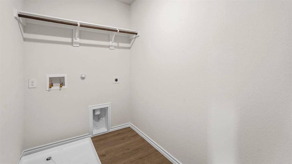 5610 Gannet Place, Crandall, TX 75114 Laundry area with wood-finish flooring, white baseboards, a built-in shelf with hanging rod, and washer/dryer hookups
