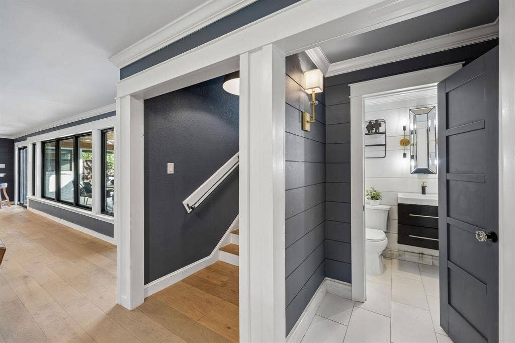 Hallway featuring neutral flooring, decorative wall treatments and access to the staircase and updated half bath.