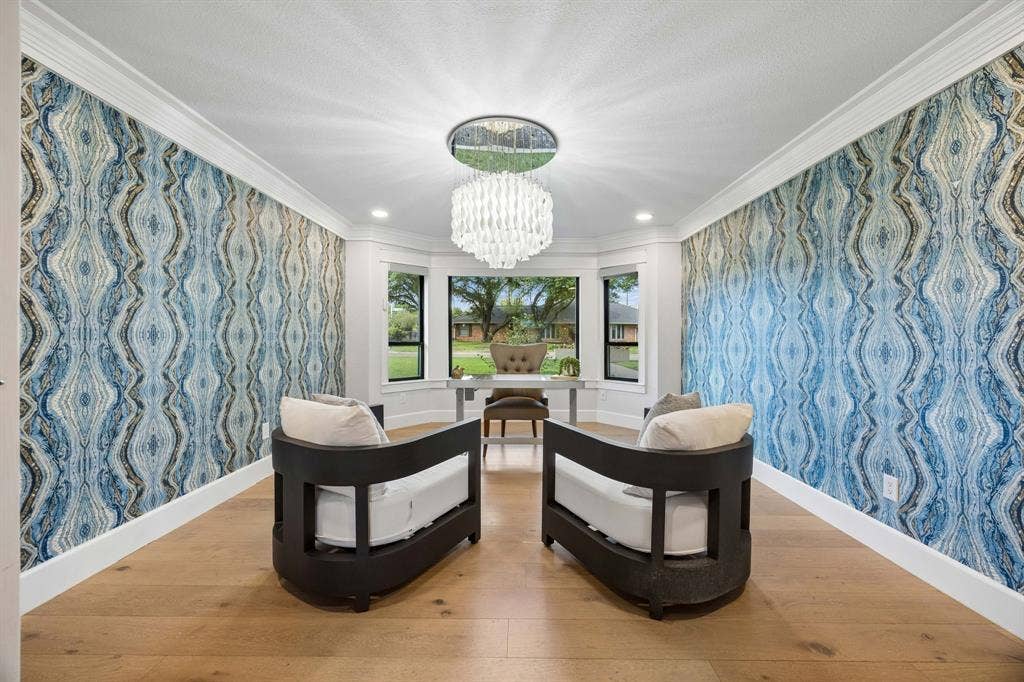 Stunning designer wallpaper, wood floors, a statement chandelier and a wall of windows overlooking the front yard with electric shades complete this inhome office.