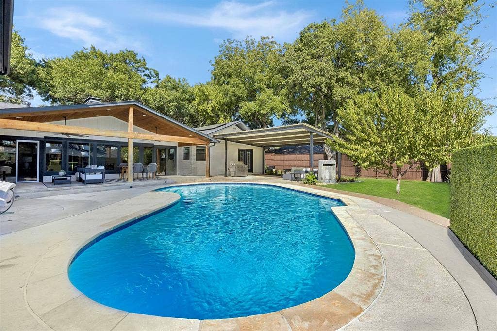 Resort-style backyard featuring a sparkling pool, two expansive covered patios, outdoor entertaining area and lush landscaping surrounded by mature trees.