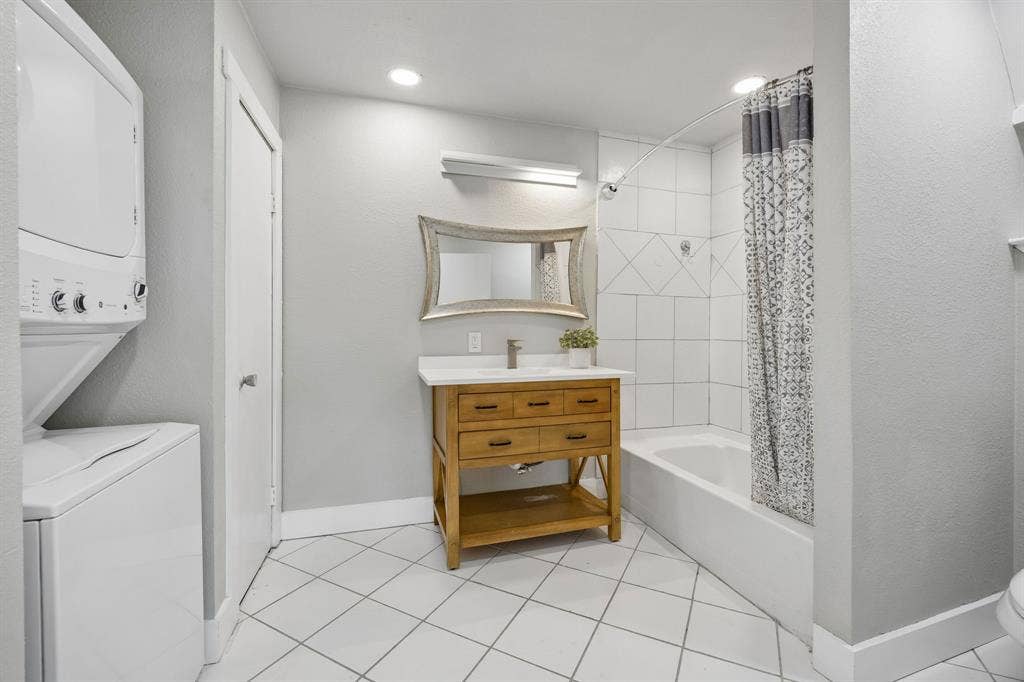 Upstairs guest suite bath featuring a tub and shower combination, wood vanity and convenient in-suite laundry connections.