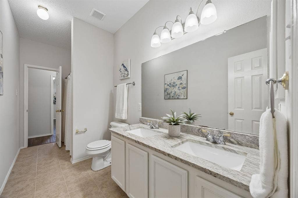 A Hall Bath Built for Busy Mornings – Dual sinks with a granite vanity top provide extra counter space and functionality, while the long bath layout keeps the vanity area separate from the tub and shower area.