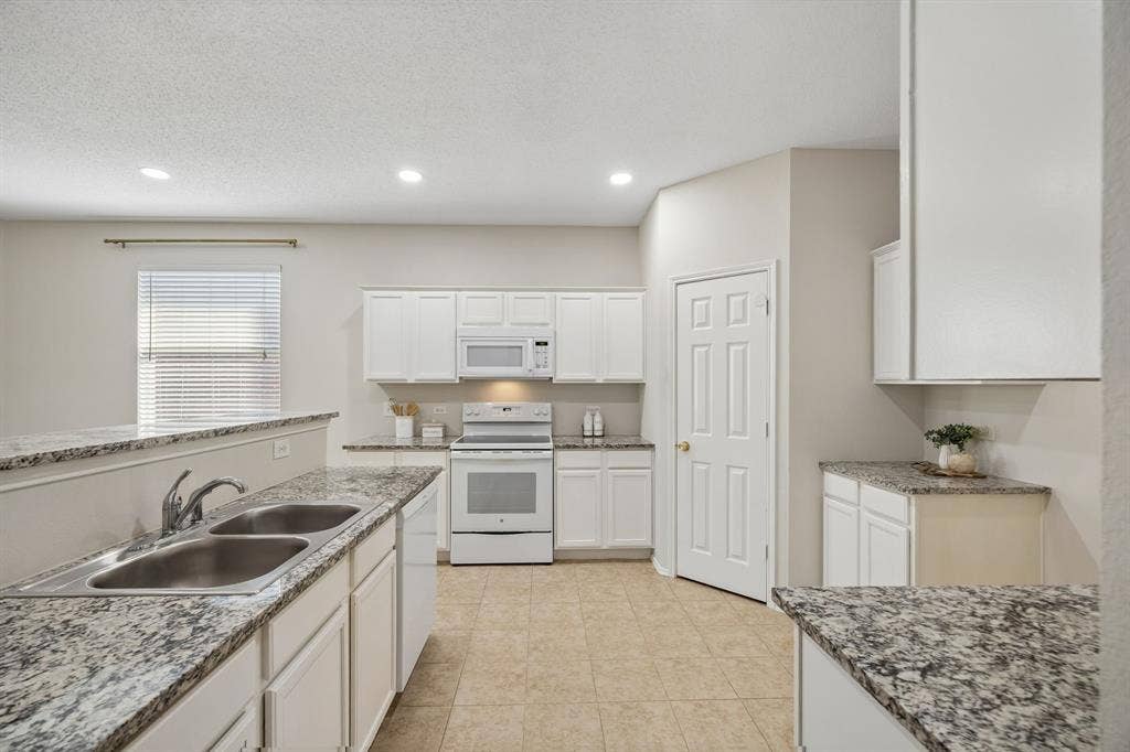 Storage and Counter Space Where You Need It – This angle showcases the kitchen’s abundant cabinetry and expansive granite surfaces, with a layout that provides dedicated areas for cooking, prep, storage, and serving.