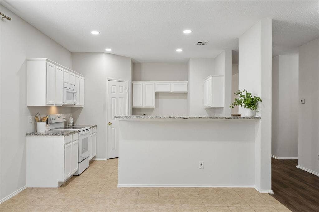A Breakfast Bar That Keeps Everyone in the Conversation – The granite-topped breakfast bar creates a natural connection between the kitchen and surrounding living spaces, adding casual seating and extra serving space without closing off the room.