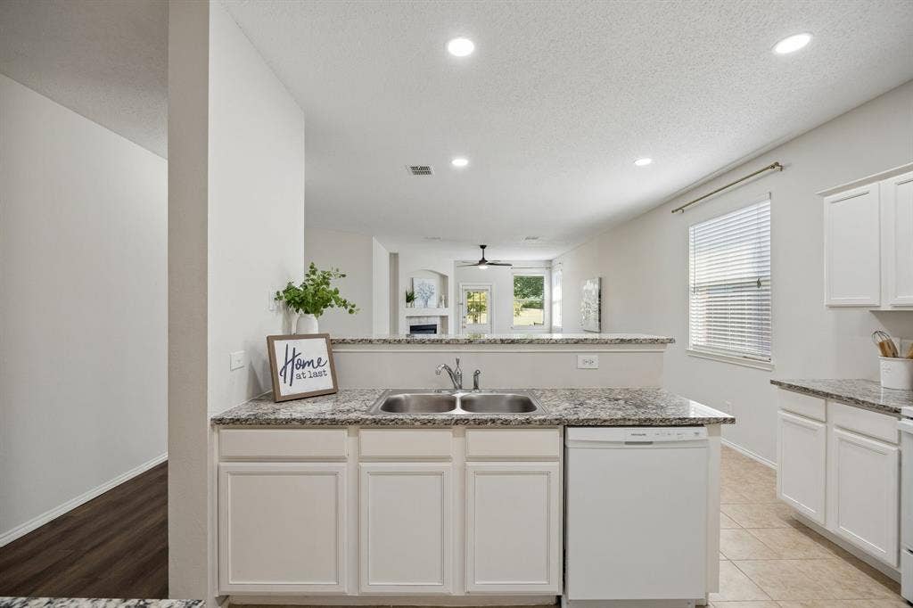 Designed for Everyday Function – A long granite workspace surrounds the double-basin sink, while additional cabinetry and counters across the kitchen provide the kind of practical storage and prep space that makes daily routines easier.