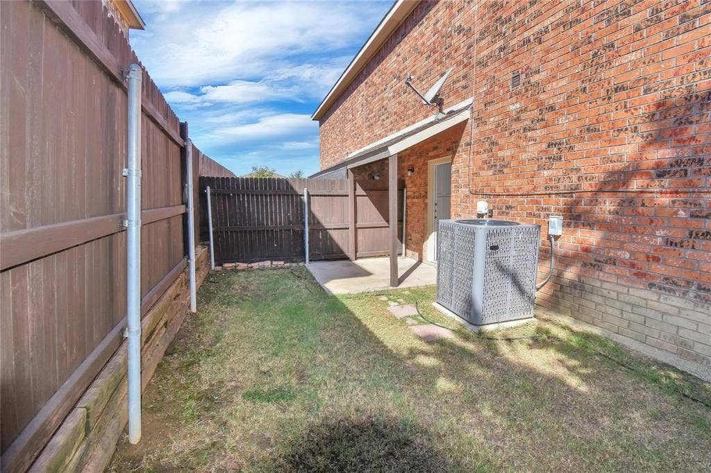 1102 Parkway Trail, Princeton, TX 75407 Red brick exterior with an attached patio, privacy fencing, and a grassy area