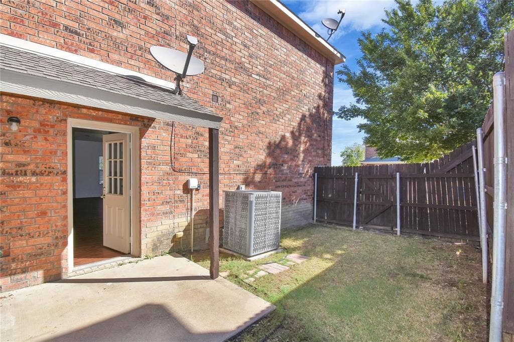 1102 Parkway Trail, Princeton, TX 75407 Brick exterior with a covered patio, solid wood privacy fencing, and a grassy area