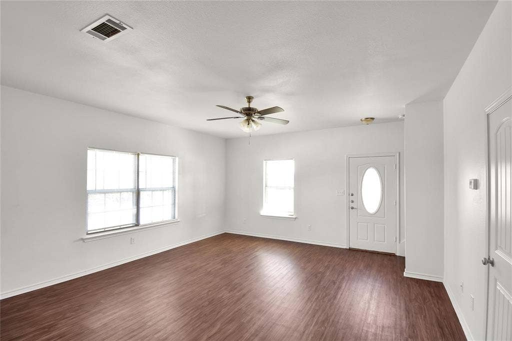 1102 Parkway Trail, Princeton, TX 75407 Wood-finish flooring, white walls, multiple windows, ceiling fan with integrated lighting, and a white front door with an oval glass insert