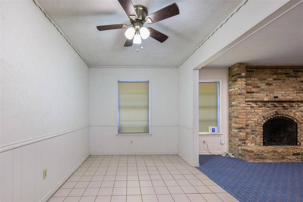635 Sherrill Boulevard, Duncanville, TX 75116 Tile flooring, white wall paneling, brick fireplace, and a ceiling fan with integrated lighting