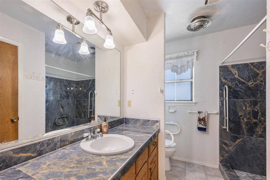 635 Sherrill Boulevard, Duncanville, TX 75116 Vanity with integrated sink, patterned countertop, and mirrored wall