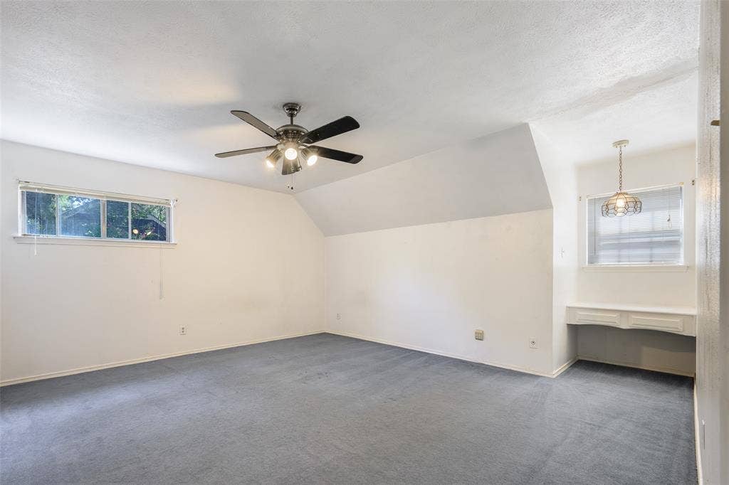 635 Sherrill Boulevard, Duncanville, TX 75116 Expansive room featuring sloped ceilings, a ceiling fan with integrated lighting, a built-in desk, and a decorative pendant light fixture