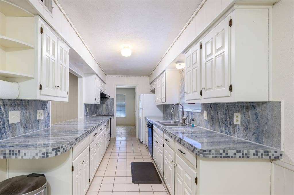 635 Sherrill Boulevard, Duncanville, TX 75116 White cabinetry with dark hardware, stone-look countertops with tile trim, ceramic tile flooring, and integrated dual basin sink