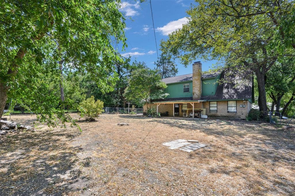 635 Sherrill Boulevard, Duncanville, TX 75116 Expansive backyard with mature trees, a covered patio, and a prominent brick chimney