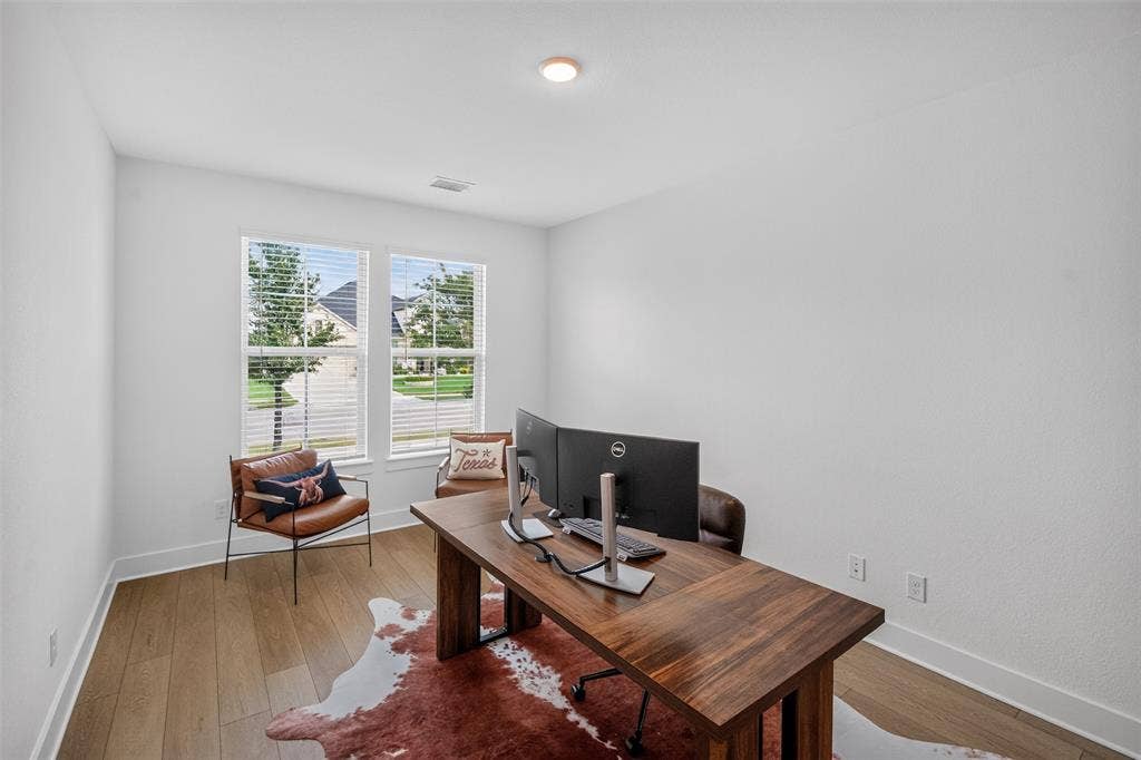 Bright room with two windows, wood-finish flooring, and a recessed ceiling light