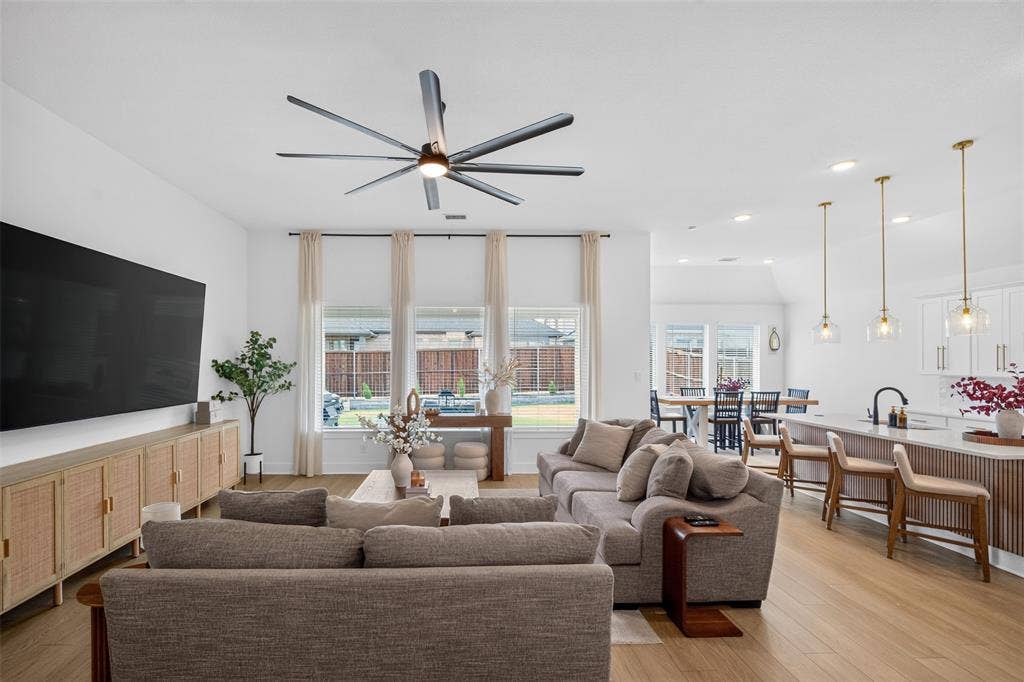 Open-concept living space featuring wood-finish flooring, recessed lighting, and a multi-blade ceiling fan