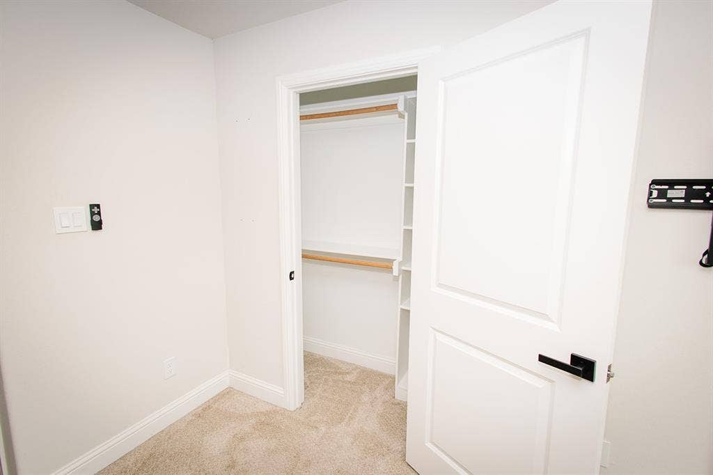 104 S Hawthorne Street, Granbury, TX 76048 2nd closet in master Closet with wood-finish shelving and hanging rod