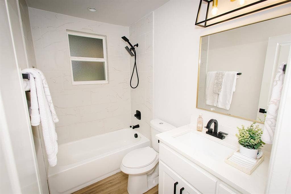 104 S Hawthorne Street, Granbury, TX 76048 Guest bathroom White vanity with dark hardware, a rectangular undermount sink, and a single-handle faucet
