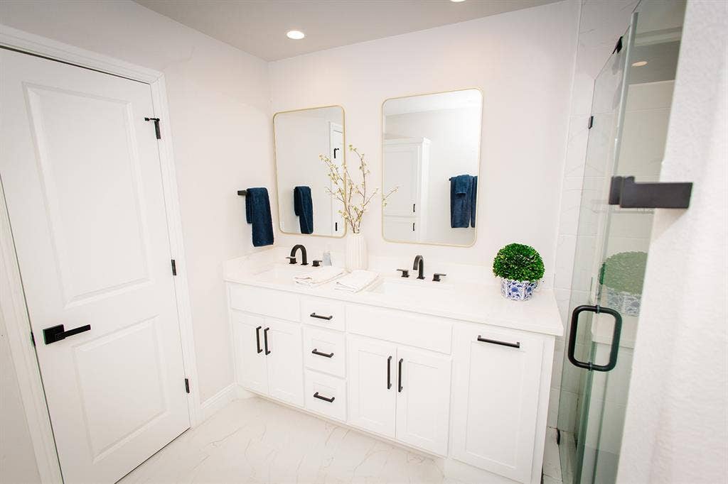 104 S Hawthorne Street, Granbury, TX 76048 Master bath Dual vanity with integrated sinks, matte black fixtures, and gold-framed mirrors