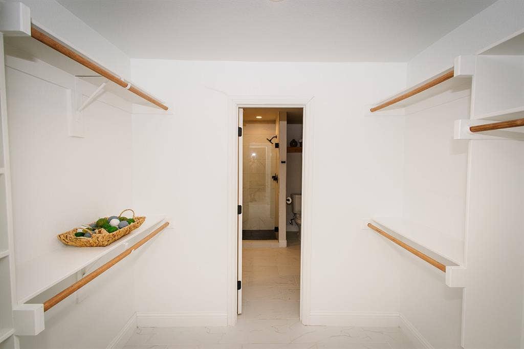 104 S Hawthorne Street, Granbury, TX 76048 Walk-in closet with white shelving and wood hanging rods