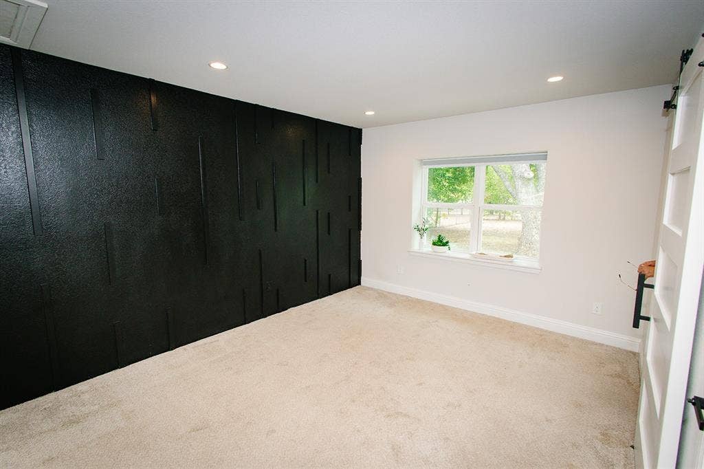 104 S Hawthorne Street, Granbury, TX 76048 Master bedroom Textured accent wall, recessed ceiling lighting, light-toned carpeting, white window trim, and white walls