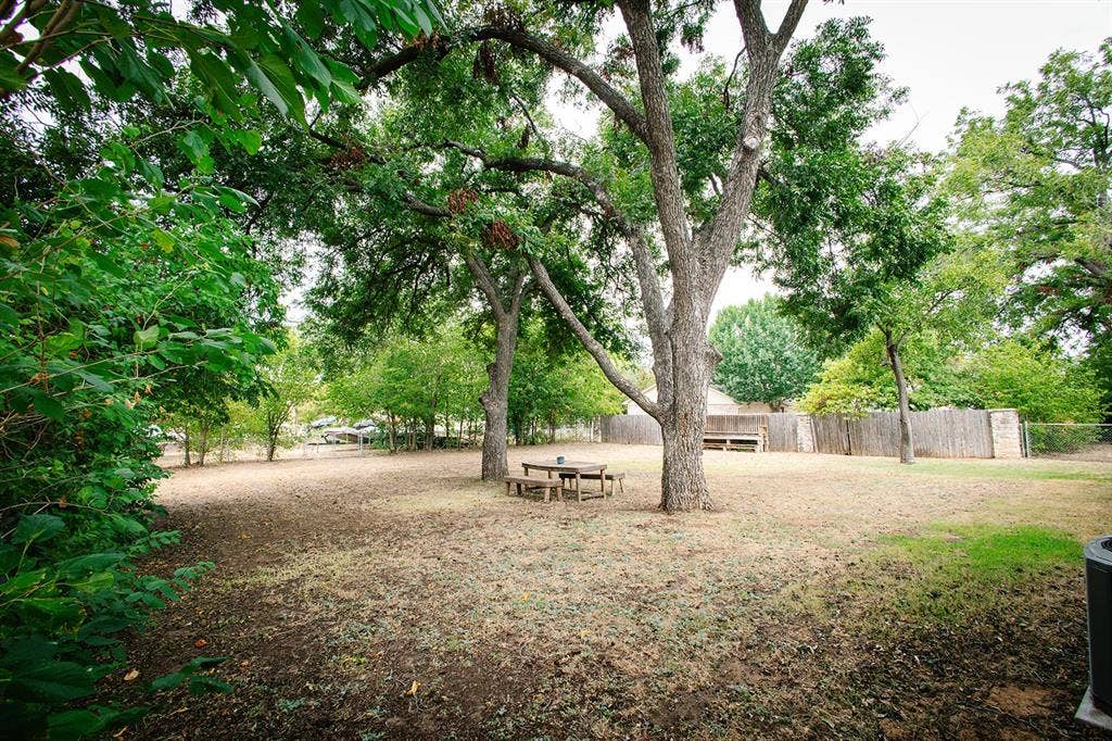 104 S Hawthorne Street, Granbury, TX 76048 Expansive outdoor space featuring mature trees, a wooden fence, and a chain-link fence