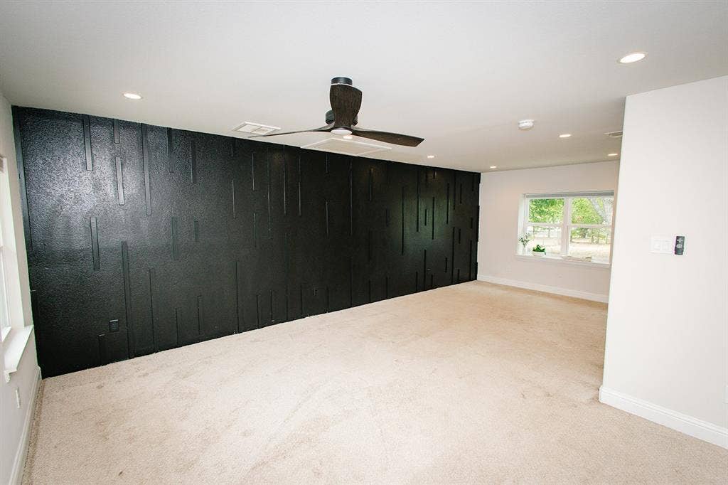 104 S Hawthorne Street, Granbury, TX 76048 Master bedroom Textured accent wall, ceiling fan, recessed lighting, white trim, and multiple windows