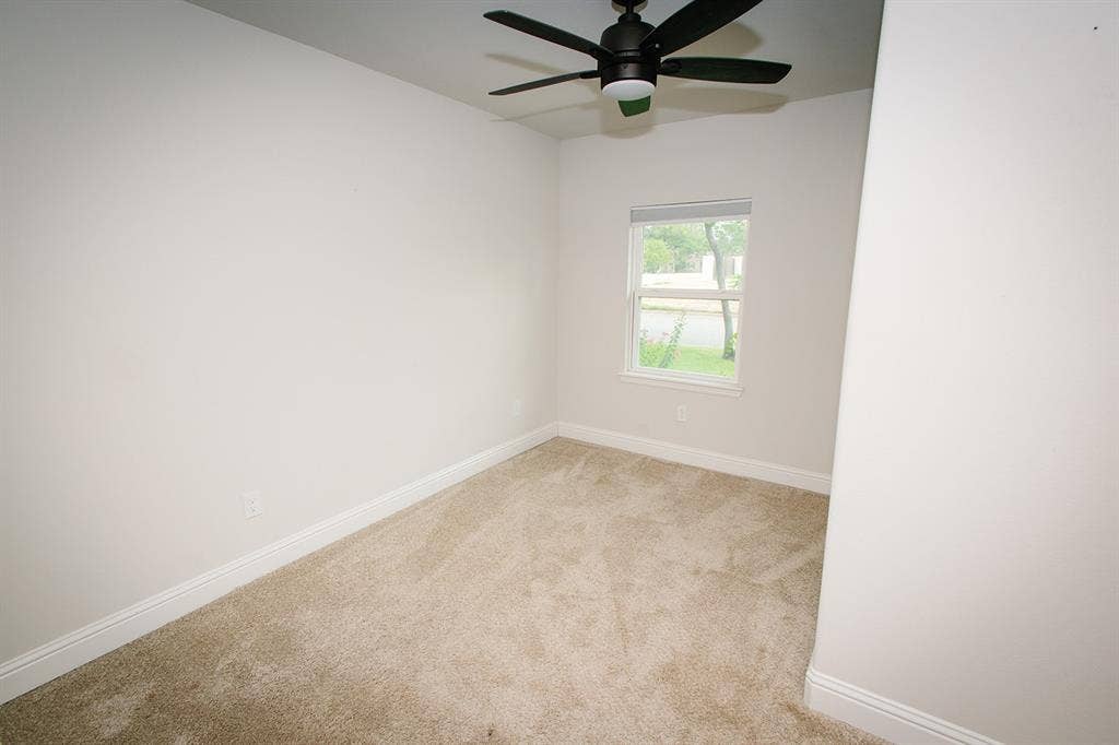 104 S Hawthorne Street, Granbury, TX 76048 BedroomWall-to-wall carpeting, single window with exterior scenery, ceiling fan with integrated lighting, and white baseboards